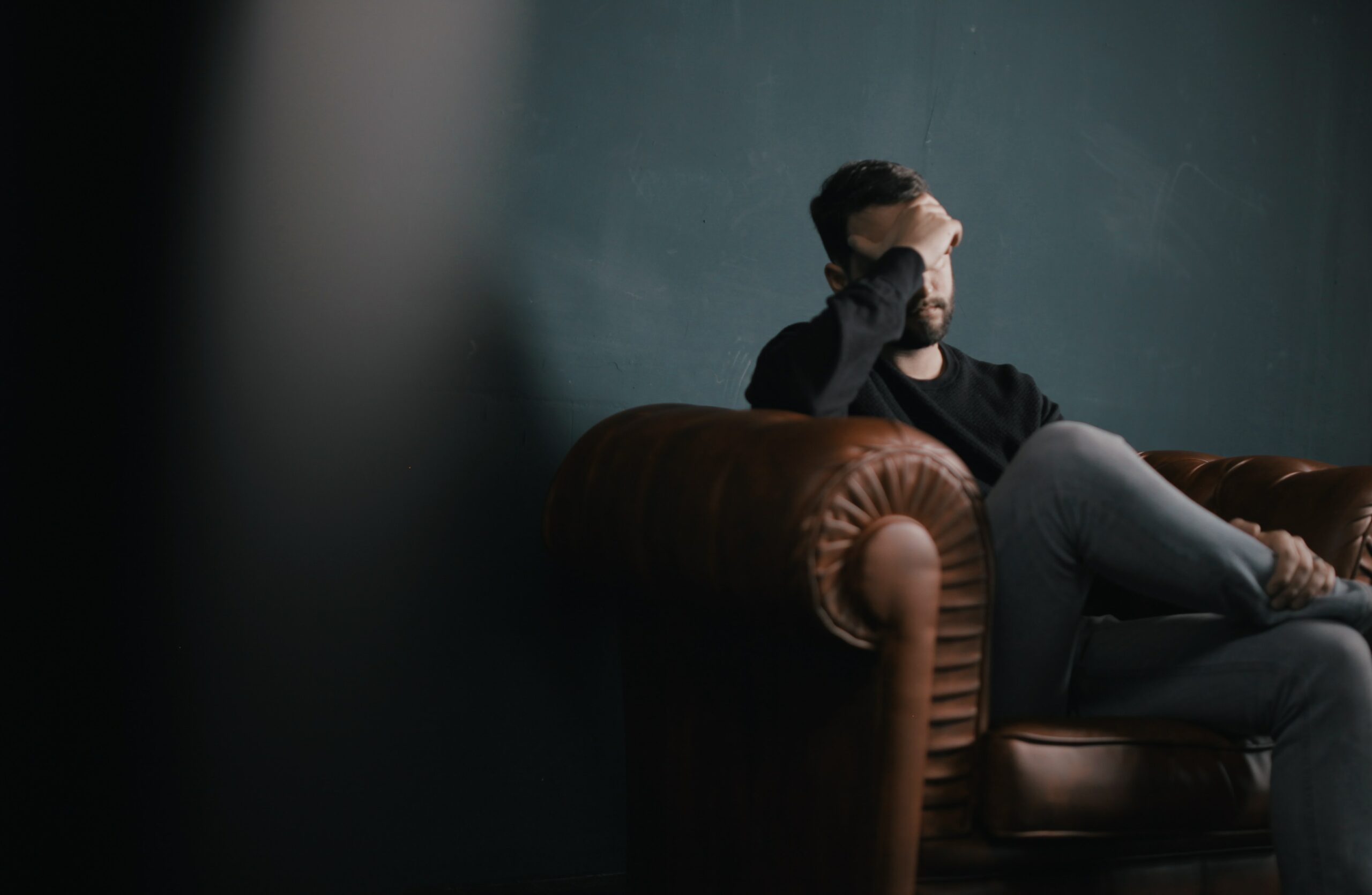 Person sat on sofa with head in hands